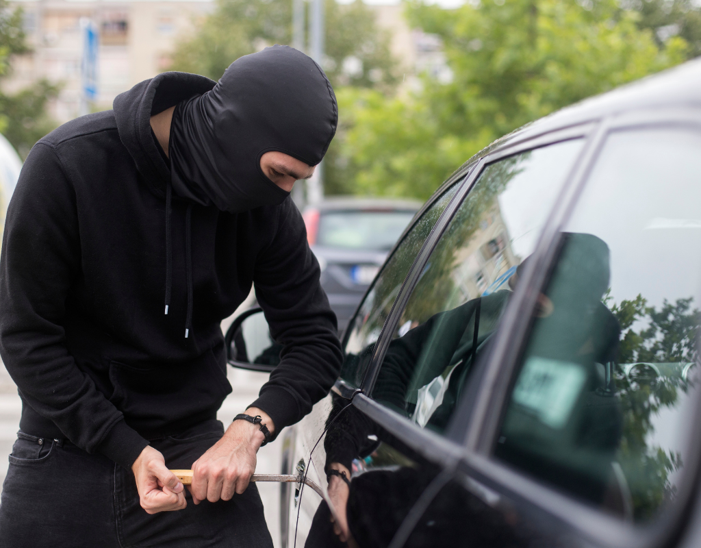 person with black balaclava trying to break into car